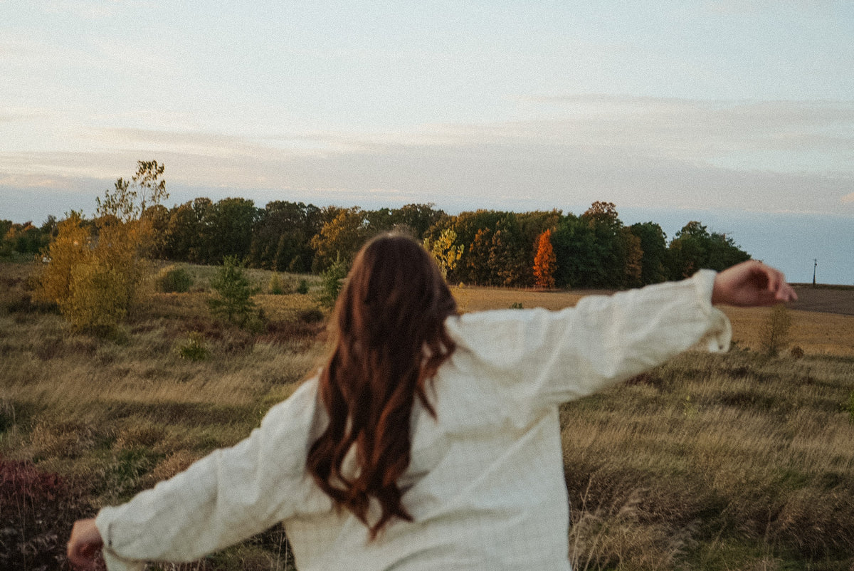 Mulher de braços abertos num campo ao ar livre